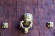 Heurtoir de porte en forme de tête de lion sur porte en fer peinte imitation bois.