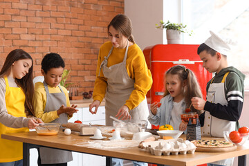 Canvas Print - Female chef with group of little children preparing pizza during cooking class in kitchen