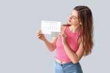 Fototapeta  - Young woman with contraceptive pills and menstrual calendar on light background