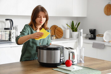 Sticker - Young woman cleaning electric multi cooker in kitchen