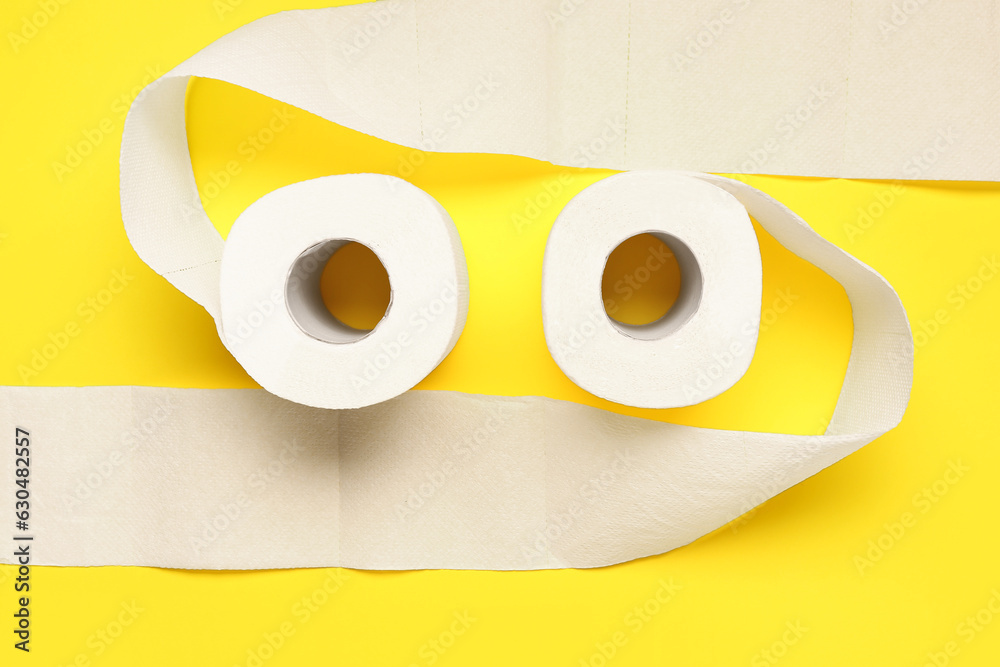 Rolls of toilet paper on yellow background