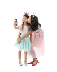 Canvas Print - Asian mother with her little daughter in crowns taking selfie on white background