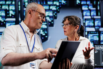 Poster - Elderly servicemen running analysis on supercomputers helping businesses manage databases, host websites and store files. Meticulous repairmen auditing high tech server farm electronics