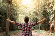 © kieferpix - Young man in autumn forest raising arms, expressing carefree happiness and connection with nature.