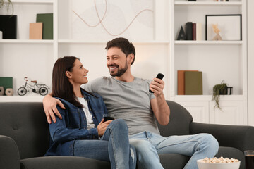 Poster - Happy couple spending time together at home. Man changing TV channels with remote control