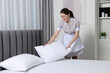 © New Africa - Young maid making bed in hotel room