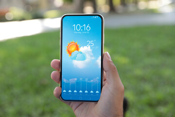 Wall Mural - man checking weather using app on smartphone outdoors, closeup. data and illustration of sun with cl