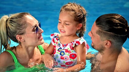 Poster - Happy parents kissing their smiling daughter while swimming in the pool. Slow motion