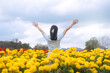 © dodotone - Rear view of young woman traveler spread open arms standing at botanical yellow flower park field