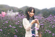 Outdoor travel asian woman using mobile phone in wild flower blossom park field