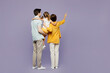 © ViDi Studio - Full body back rear view young parents mom dad child kid girl 6 years old wearing blue yellow casual clothes hold daughter point finger aside isolated on plain purple background. Family day concept.
