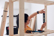 © astrosystem - Woman assembling new wooden shelf and furniture in the apartment.