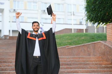 Poster - Portrait of indian handsome male graduate in graduation robe.