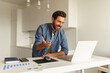 © Daria - Male freelancer have a video conference from laptop during distance work from home kitchen