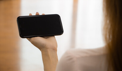Poster - Mockup image of woman holding mobile phone with blank black screen. template for artwork design.