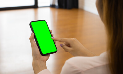 Poster - Mockup image of woman pointing finger at mobile phone blank green screen. template for artwork design.