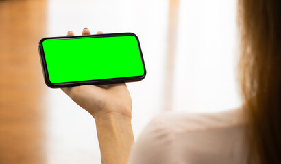 Poster - Mockup image of woman holding mobile phone with blank green screen. template for artwork design.