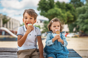 two children eating ice cream, one preschooler boy and one toddler girl, brother and sister sitting 