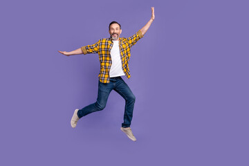 Wall Mural - Photo of excited positive man wear stylish checkered denim clothes have fun walk empty space isolated on purple color background