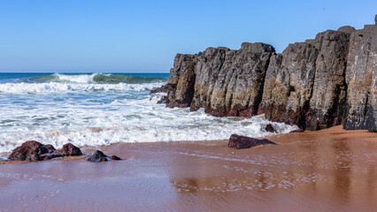 Wall Mural - Beach Black Rock Wall Headland Wave Wash Ocean Blue Horizon.