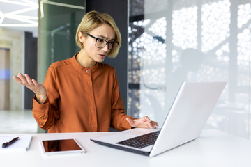 Dissatisfied and upset woman at workplace looking at laptop screen, business woman received error and refusal of online banking transaction, female worker disappointed inside office.