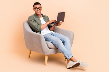 Sticker - Full body photo of cheerful friendly person sitting comfy chair use wireless netbook isolated on beige color background