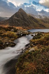 Sticker - Tranquil mountain stream flows through a lush green meadow in Tryfan mountain, Wales