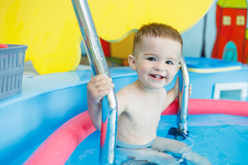 Wall Mural - A 2-year-old little boy learns to swim in a clean pool. Child development. Developmental pool for teaching children to swim. Swimming school