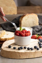 Poster - A vertical shot of a fork dipping into a bowl of fresh raspberries in a bowl