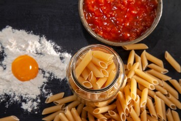 Poster - Variety of fresh pasta with flour, red sauce and eggs spread out on a wooden table