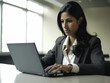 © Justlight - A woman with a laptop typing away on her computer in a corporate office..
