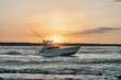 Large fishing vessel is seen navigating through the choppy waters of the open ocean at sunset