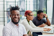© Katsiaryna - young African American man posing for the camera while sitting at a table in front of his colleagues