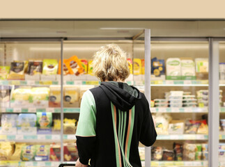  Man choosing frozen food from a supermarket freezer., reading product information