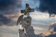 Ornate sculpture featuring an angel atop a large cross, standing atop a stone pedestal