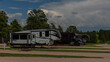 Rv motorhome and camper trailers parked at large campsite under cloudy sky