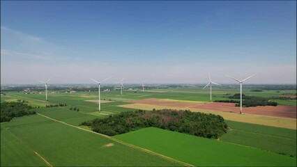 Canvas Print - Drone shot over windmills in a green fields at countrysided under a blue sky