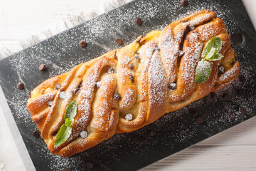 Wall Mural - Dessert festive braided sweet bread with chocolate and custard close-up on a slate board on the table. Horizontal top view from above