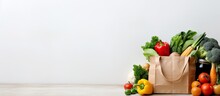 Background Of Healthy Food Delivery. It Features A Paper Bag Filled With Vegan And Vegetarian Food, Including Fruits And Vegetables. Has A White Background With Copy Space, Making It Suitable For