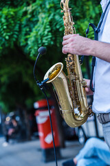 jazz musician artist playing saxophone in the street of a european city. a street musician plays sax