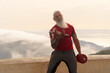 Senior man with white beard doing sport exercises with two dumbells outdoor, close up view, healthy and happy lifestyle concept