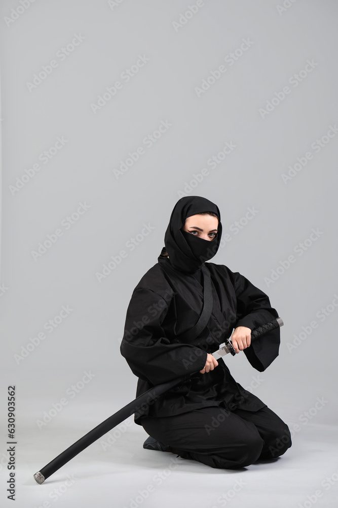 Female ninja with sword on grey background