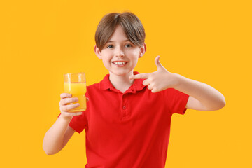 Sticker - Little boy pointing at glass of orange juice on color background