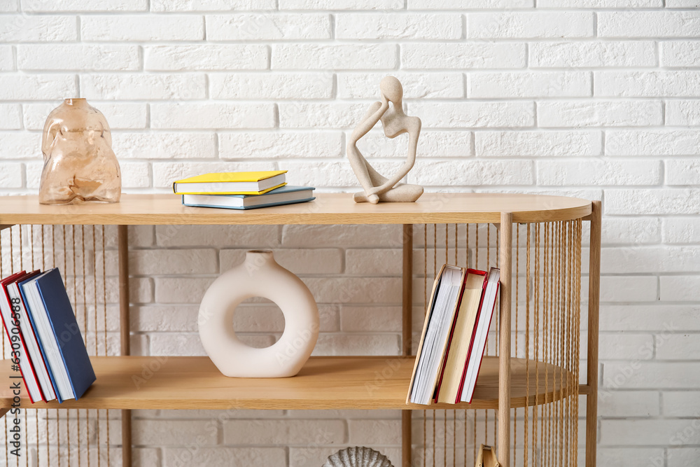 Bookshelf with decor near white brick wall