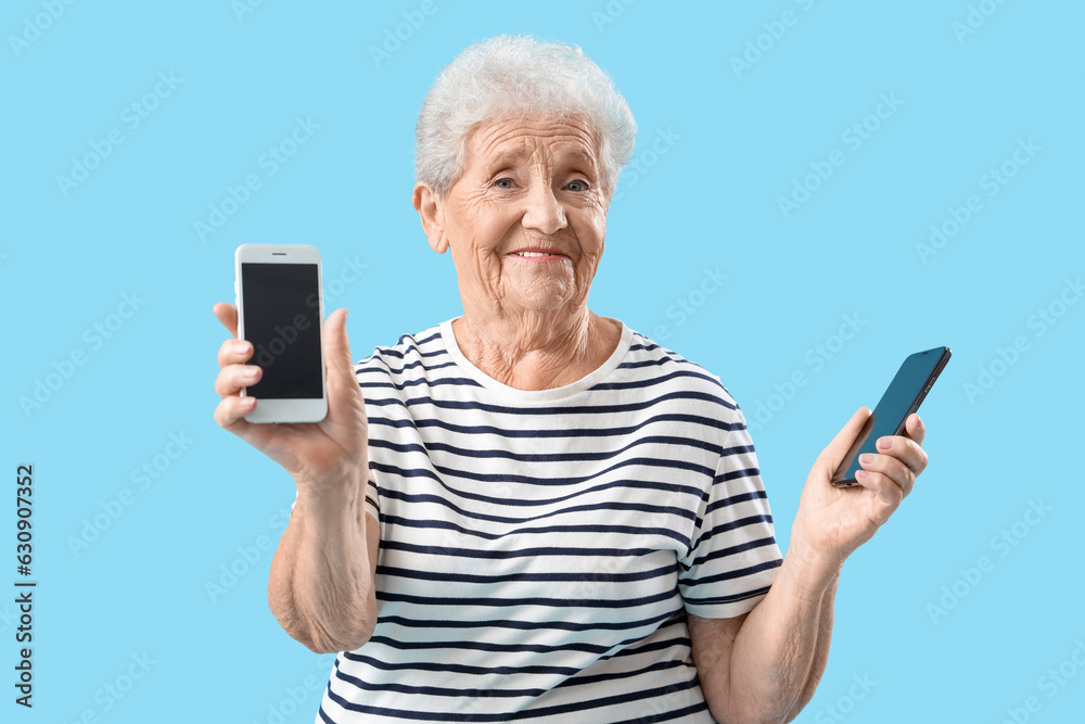 Senior woman with mobile phones on blue background