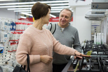 Wall Mural - Happy spouses of mature age, who came to the electronics and home appliances store, choose a gas stove to buy it