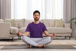 © New Africa - Man meditating on yoga mat at home. Harmony and zen