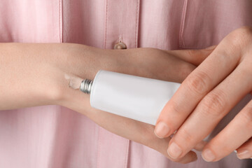 Poster - Woman squeezing out ointment from tube on her hand, closeup