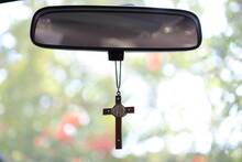 Closeup wooden cross hanging from front steering wheel and car console. Concept, amulet, amulet to prevent accidents. Faith, faith, holy to God to protect you when driving.