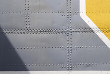 Riveted With Button-head Rivets Metal Plate - Side Of An Aircraft - Painted In Gray, White And Yellow As A Background